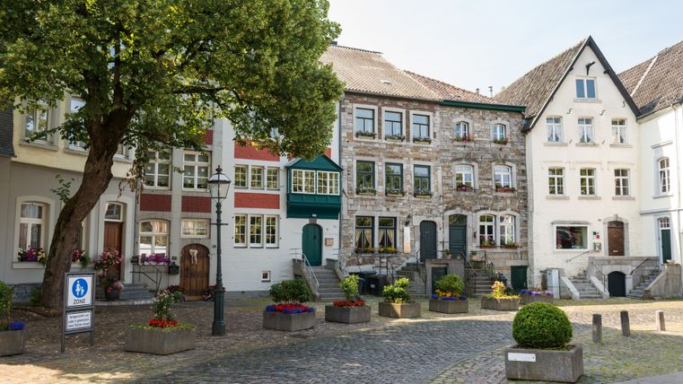 Historische Häuser in Kornelimünster mit Kopfsteinpflaster und Blumenschmuck.