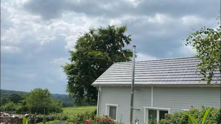 Ein charmantes Haus in der Natur mit einem grünen Garten. Der Himmel ist bewölkt und die Landschaft ist ruhig.