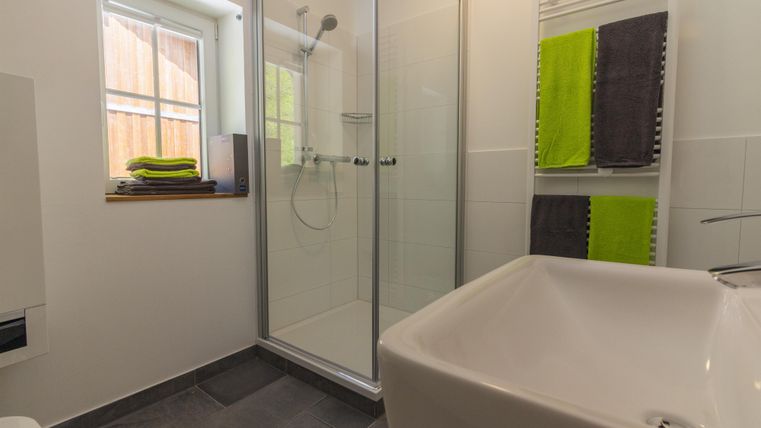 Ein modernes Badezimmer mit einer Dusche und einer weißen Badewanne. Frische Handtücher in lebhaften Farben sind ordentlich aufgehängt.