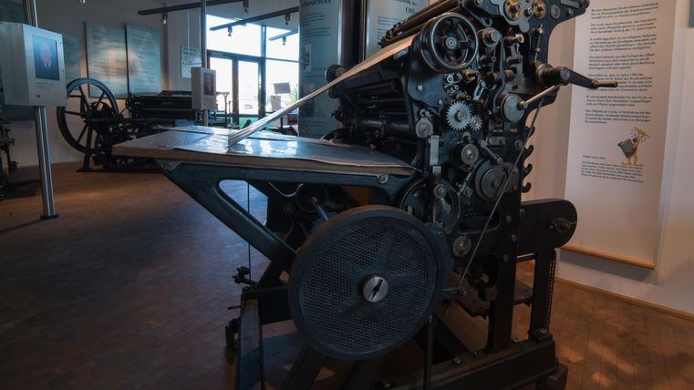 Eine alte Druckmaschine steht in einem Museum. Sie zeigt die Technik des Druckens aus vergangener Zeit.