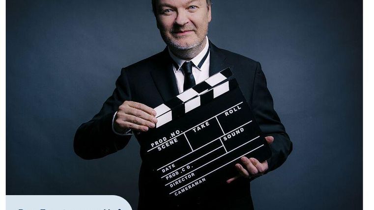 Ein Musiker spielt Cello auf der Bühne. Das Bild zeigt konzentrierte Musikalität und einen melancholischen Ausdruck.