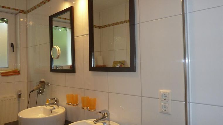 Ein modernes Badezimmer mit zwei Waschbecken und großen Spiegeln. Die Wände sind hellfließend gefliest und verleihen dem Raum eine saubere Atmosphäre.