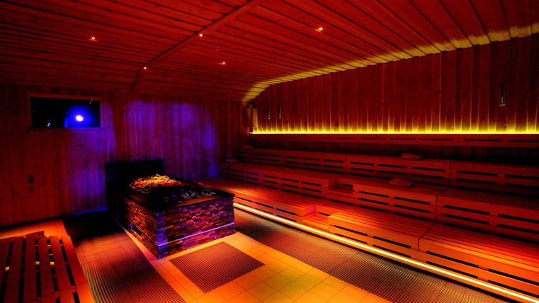 Eine entspannende Sauna mit holzverkleideten Wänden und sanfter Beleuchtung. Die Atmosphäre ist ruhig und einladend.