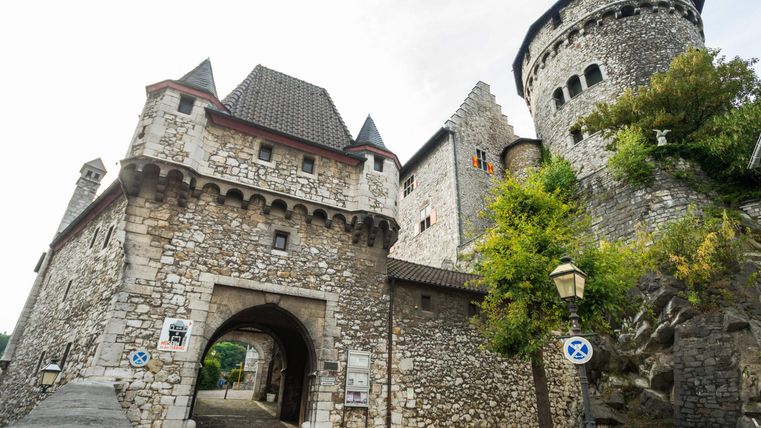 Eine beeindruckende Burg mit Steinmauern und hohen Türmen. Die Umgebung ist grün und einladend.