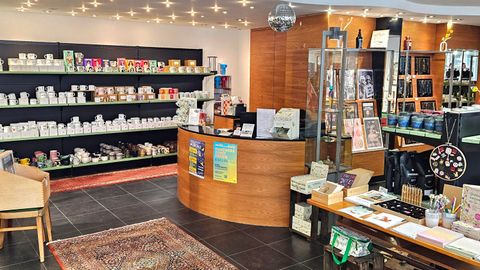 Ein gemütlicher Laden mit Regalen voller Produkte und einem Empfangstresen. Die warmen Lichter schaffen eine einladende Atmosphäre.