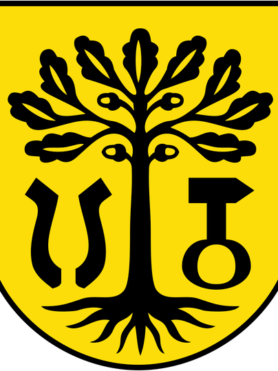 Ein Wappen mit einem schwarzen Baum auf gelbem Hintergrund. Neben dem Baum befinden sich symmetrische, stilisierte Symbole.