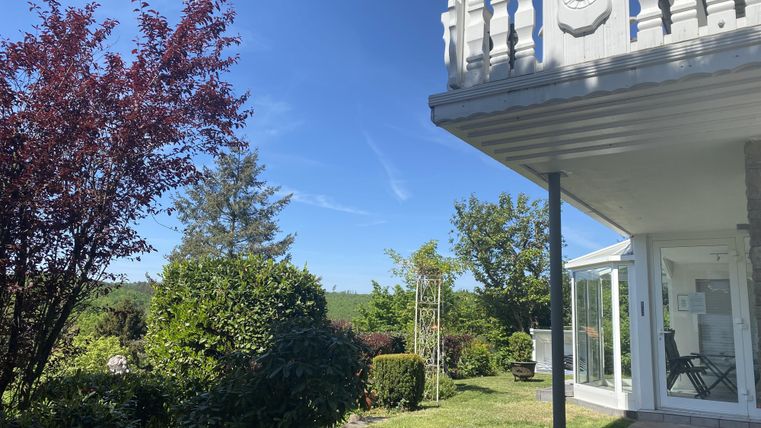 Ein modernes Haus mit einem schönen Garten. Der Himmel ist klar und blau, umgeben von grünen Pflanzen.