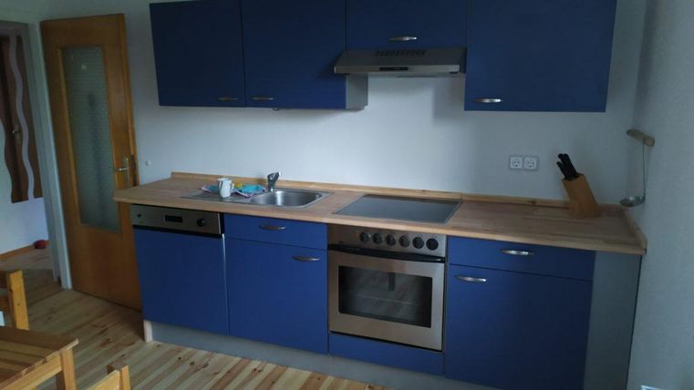 Eine moderne Küche mit blauen Schränken und einer Holzarbeitsplatte. Die Ausstattung umfasst einen Herd, einen Ofen und eine Spüle.