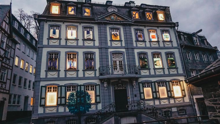 Ein historisches Gebäude mit bunten Fenstern und einer schönen Fassade. Der Abendhimmel ist grau und verleiht der Szene eine ruhige Atmosphäre.