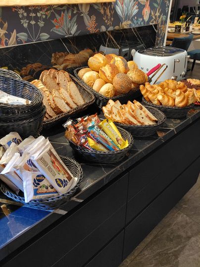 Eine Auswahl an frischem Brot und Brötchen in Körben. Im Vordergrund sind auch Snacks und Süßigkeiten zu sehen.
