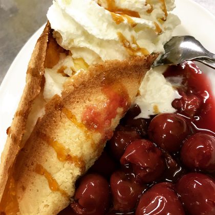Ein köstlicher Kuchen mit Sahne und Kirschen in roter Sauce. Der Kuchen ist knusprig und frisch verziert.