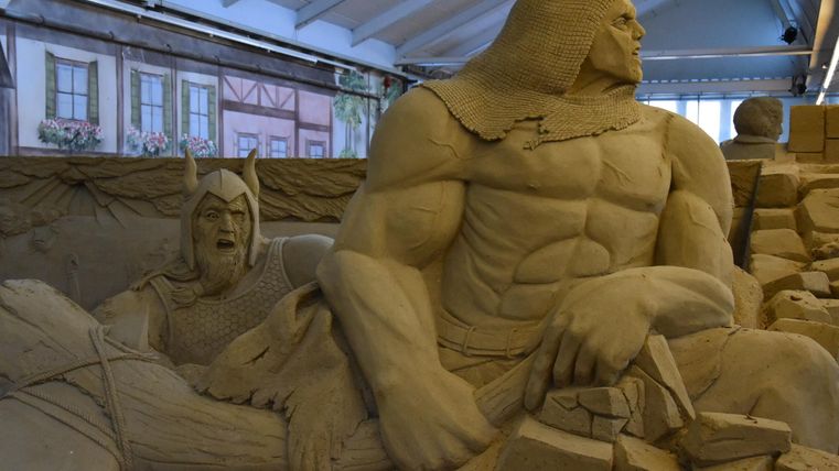 Eine beeindruckende Sandskulptur zeigt zwei mächtige Figuren. Die Details der Kunstwerke sind klar und gut ausgearbeitet.