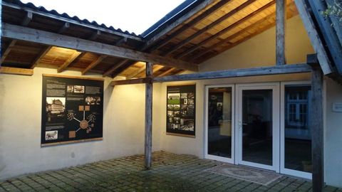 Ein überdachter Eingangsbereich mit großen Fenstern und informativen Posterwänden. Die Beleuchtung sorgt für eine einladende Atmosphäre in der Dämmerung.