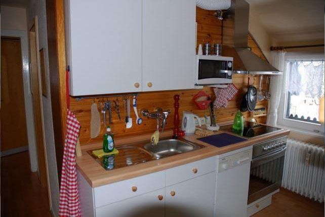 Eine gemütliche Küche mit Holzverkleidung und modernen Geräten. Der Raum ist ordentlich und gut ausgestattet.