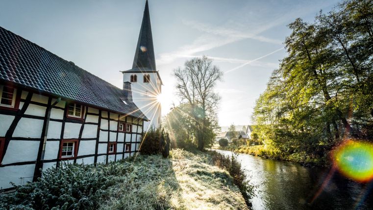 Fachwerkhaus und Kirche in Olef am Fluss bei Sonnenaufgang.