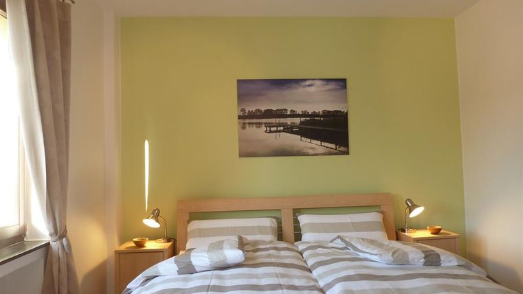 Ein gemütliches Schlafzimmer mit zwei Betten und gestreiften Bettdecken. An der Wand hängt ein Bild einer ruhigen Landschaft.