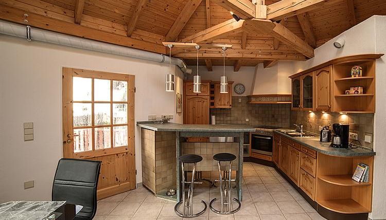 Eine moderne Küche mit Holzelementen und offenem Raum. Der Kochbereich ist mit einer Bar und modernen Geräten ausgestattet.