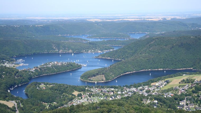 Eine malerische Aussicht auf einen Fluss mit vielen Buchten und kleinen Booten. Umgeben von sanften Hügeln und grünem Uferland.