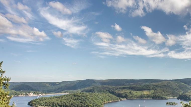 Eine malerische Landschaft mit einem großen See und mehreren kleinen Inseln. Der Himmel ist klar und mit einigen Wolken durchzogen.