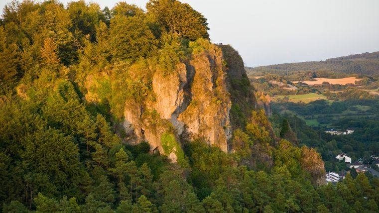 Blick auf die Munterley-Felsen in der Eifel, umgeben von Bäumen und Landschaft.