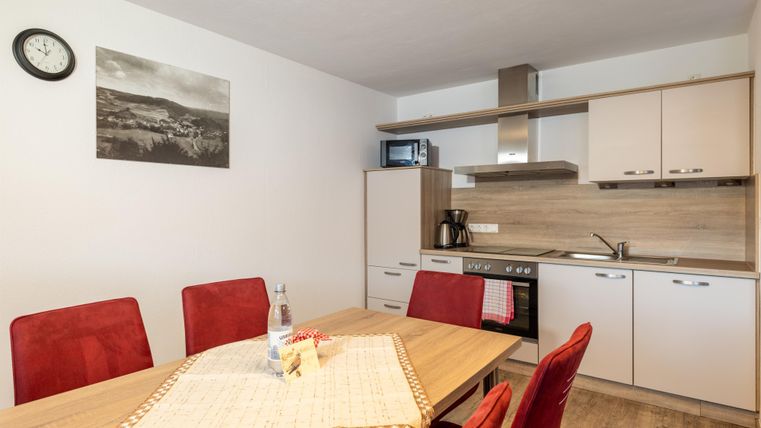 Eine moderne Küche mit einem Essbereich. Rote Stühle und helle Möbel schaffen eine einladende Atmosphäre.