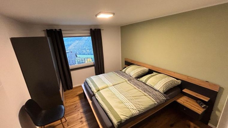 Ein modernes Schlafzimmer mit einem großen Doppelbett und einer gemütlichen Sitzecke. Das Fenster bietet einen Blick auf die Landschaft.