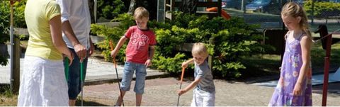 Ein Spielplatz mit Kindern, die mit Stöcken spielen. Es ist ein sonniger Tag und die Kinder haben viel Spaß.