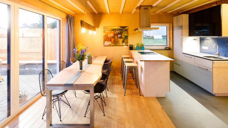 Eine moderne Küche mit einem großen Esstisch und stilvollen Stühlen. Das helle Licht schafft eine einladende Atmosphäre.