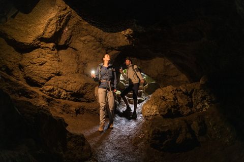Zwei Personen erkunden eine Höhle mit Taschenlampen.
