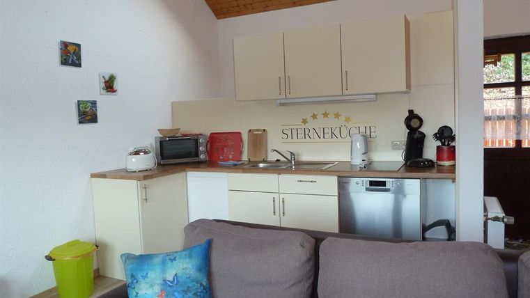 Eine modernes Kücheninterieur mit Geräten und einer gemütlichen Sitzecke. Die Wände sind hell und mit kleinen Bildern dekoriert.