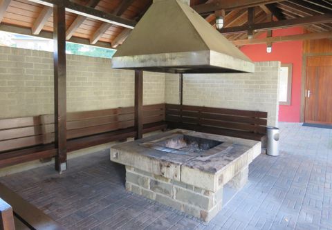 Ein Grillplatz mit einem großen Kamin und Holzbank. Der Raum ist überdacht und bietet Platz zum Entspannen.