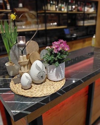 Eine schöne Dekoration auf einer Bar mit Ostereiern, Blumen und einer Kerze. Der Tisch hat eine moderne Ästhetik mit einem eleganten Marmormuster.