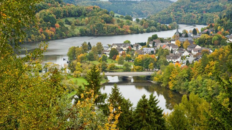 Blick auf Einruhr mit Fluss und Brücke, umgeben von herbstlichen Bäumen.