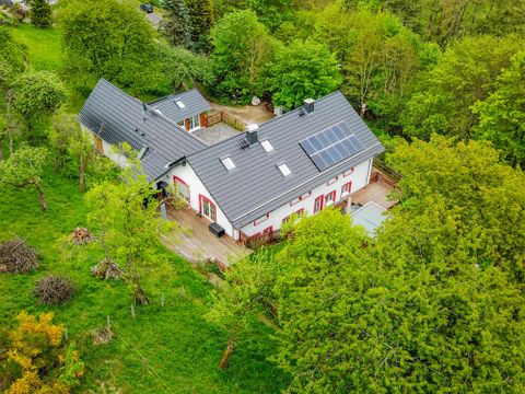 Ein modernes Haus umgeben von grünen Bäumen. Der Garten ist schön gestaltet mit einer Terrasse.