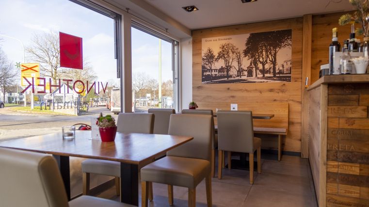 Ein gemütliches Café mit Holzmöbeln und großen Fenstern. Durch die Fenster ist eine angenehme Lichtatmosphäre zu sehen.