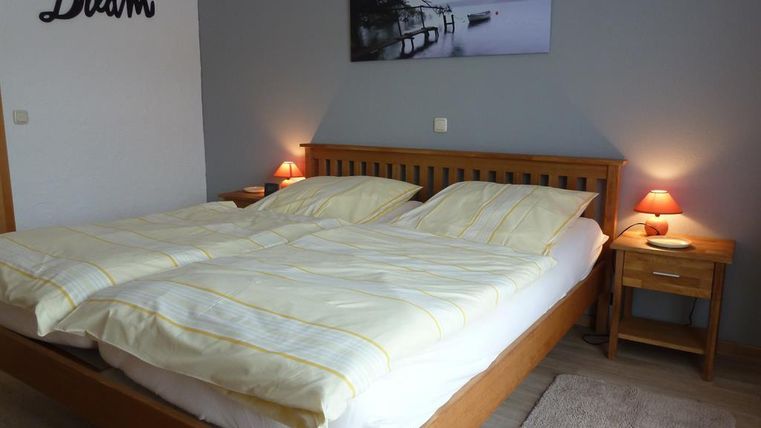 Ein modernes Schlafzimmer mit einem großen Doppelbett und sanften Beleuchtung. An der Wand hängt ein beruhigendes Landschaftsbild.