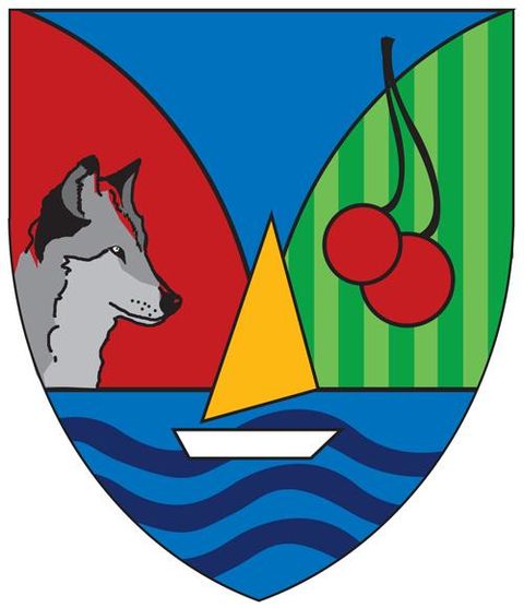 Das Wappen zeigt einen Wolf, ein Segelboot auf blauem Wasser und zwei Kirschen auf grünem Hintergrund. Die Farben sind kräftig und symbolisieren die Natur und maritime Elemente.
