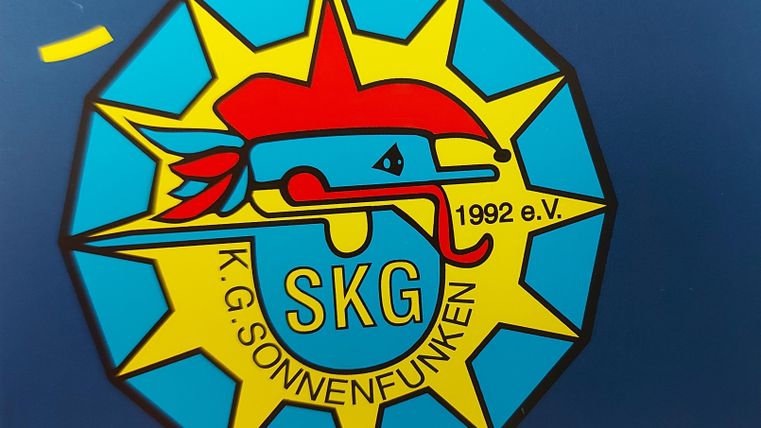 Ein buntes Logo der K.G. Sonnenfunken mit einem stilisierten Fisch und einem Sternenmotiv. Das Jahr 1992 ist ebenfalls im Design enthalten.