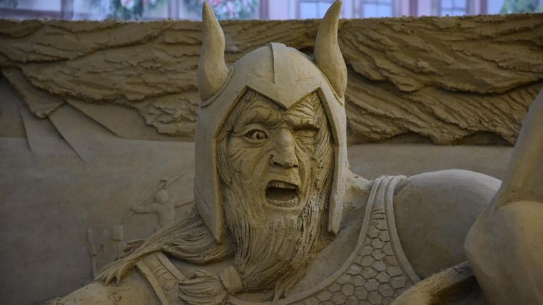 Eine beeindruckende Sandfigur eines Kriegers mit einem erschrockenen Gesichtsausdruck. Er trägt eine gehörnte Helm und eine Kettenrüstung.